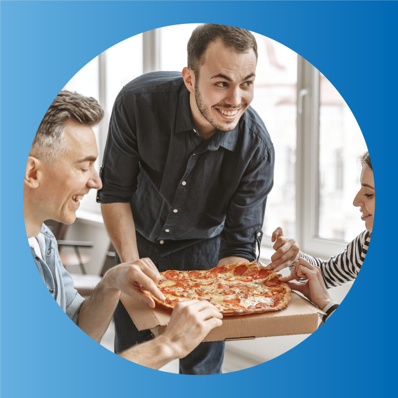 Photo d'une personne présentant une pizza à deux autres